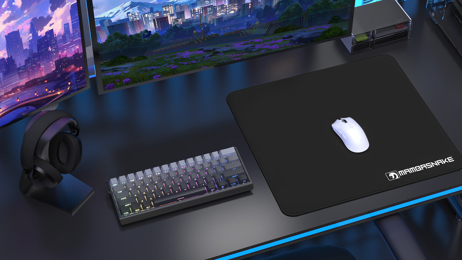 A gaming desk with dual monitors, a backlit keyboard, a white mouse on a Mambasnake mousepad, and headphones