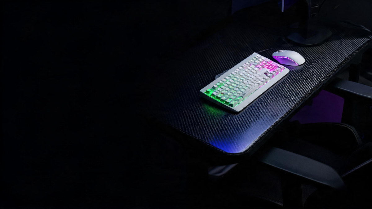 White gaming desk with a keyboard and mouse on a carbon-fiber surface, surrounded by saturated purple and neon-green lighting with dark space on the left.