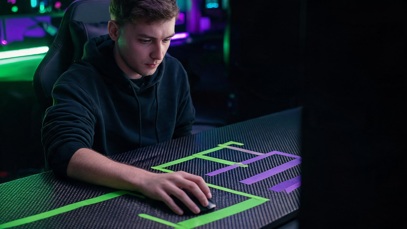 Gamer checking hand position and mouse movement space at a dark RGB-lit desk
