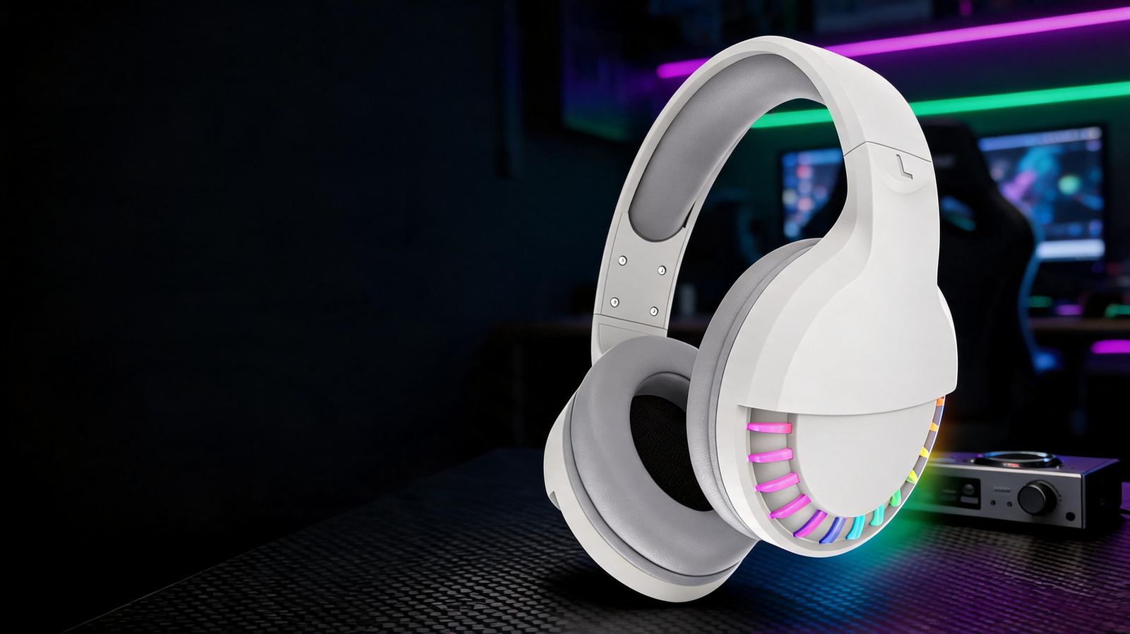 White over-ear gaming headset with illuminated earcup accents resting on a carbon-fiber gaming desk beside a glowing audio interface