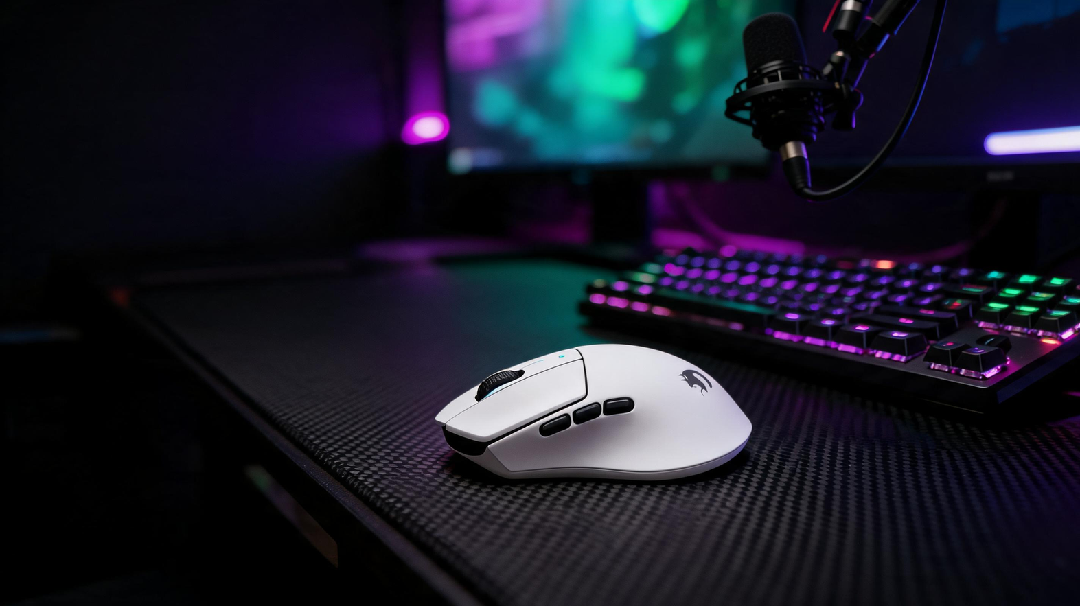 White gaming mouse on a carbon-fiber desk beside a streaming microphone, monitor glow, and purple and neon-green RGB lighting