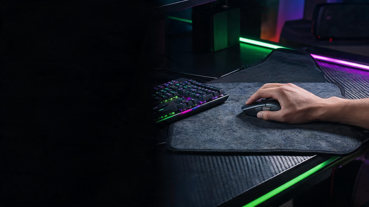 Gamer’s hand moving a mouse across a textured control surface in a dark RGB-lit gaming setup
