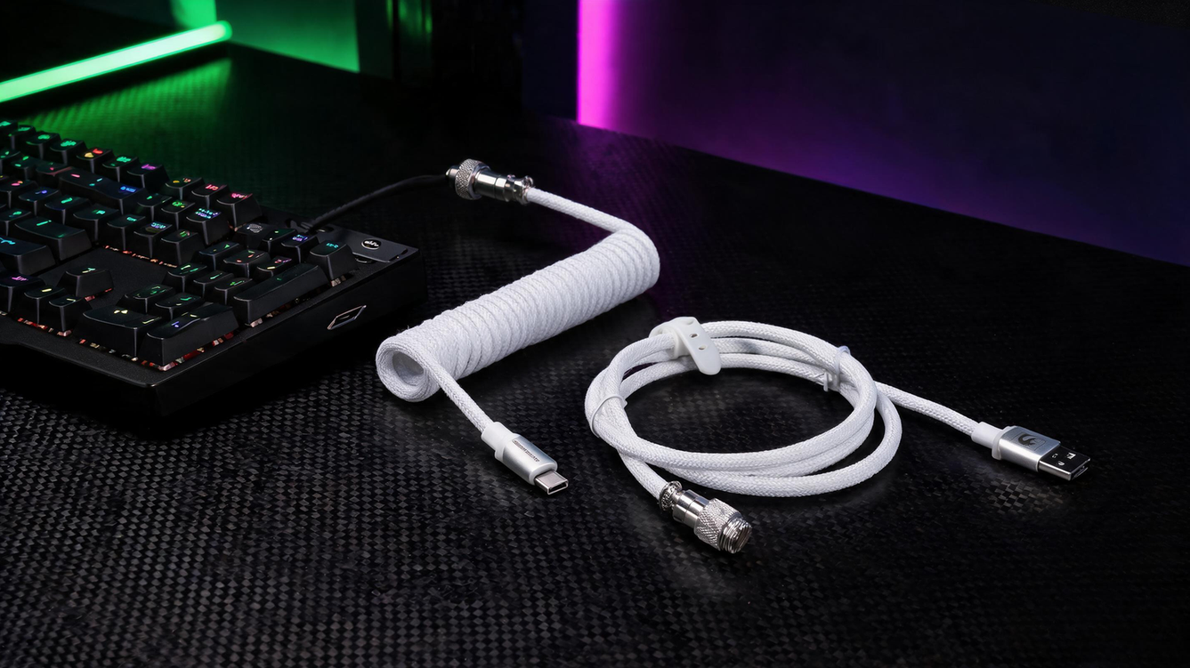 Coiled keyboard cable arranged beside a mechanical keyboard on a carbon-fiber gaming desk, with the inline connector visible in saturated green and purple lighting