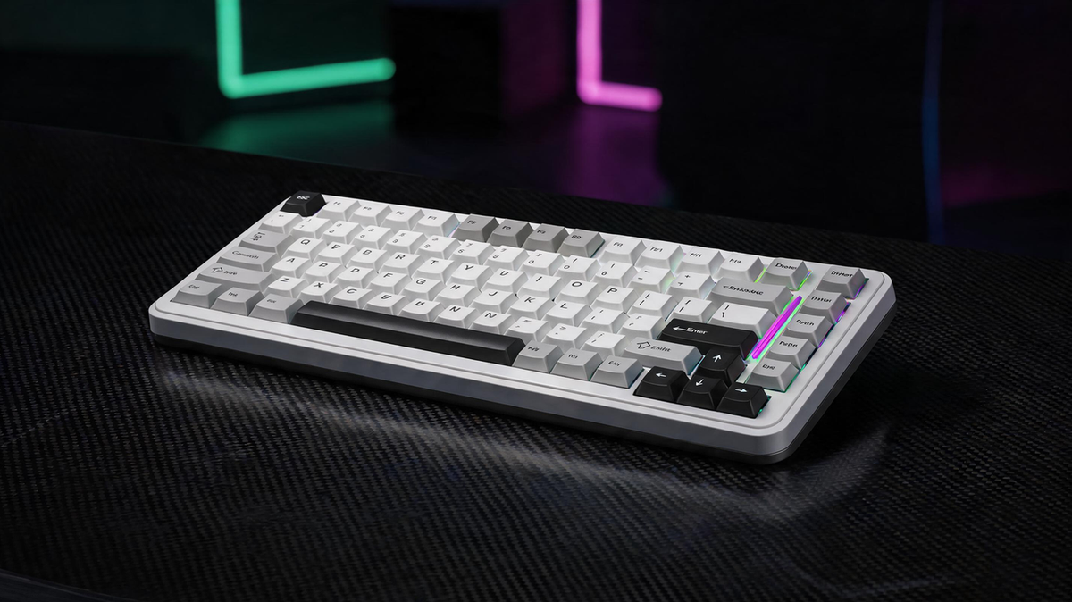 White gaming keyboard glowing on a carbon-fiber desk in a dark esports room with saturated neon lighting and open shadow space on the left