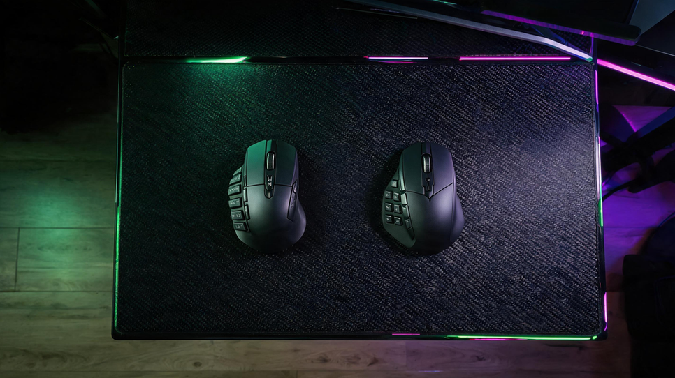 Two generic MMO gaming mice on a carbon-fiber desk in a dark RGB-lit gaming setup, one with a dense thumb-button grid and one with simpler side controls