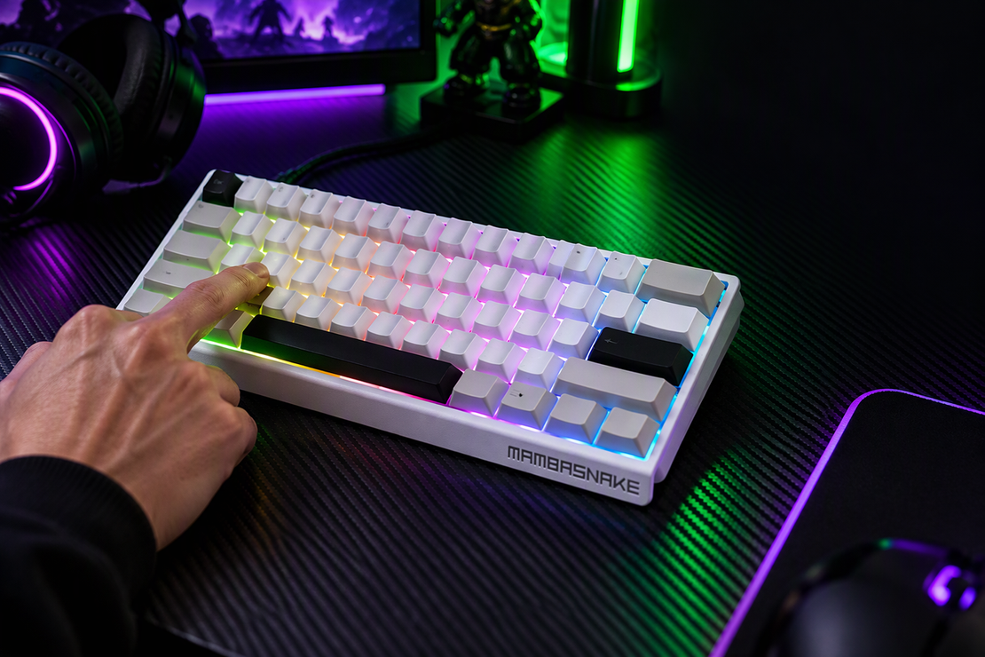 A player tests a key on a compact RGB keyboard at a dark gaming desk.