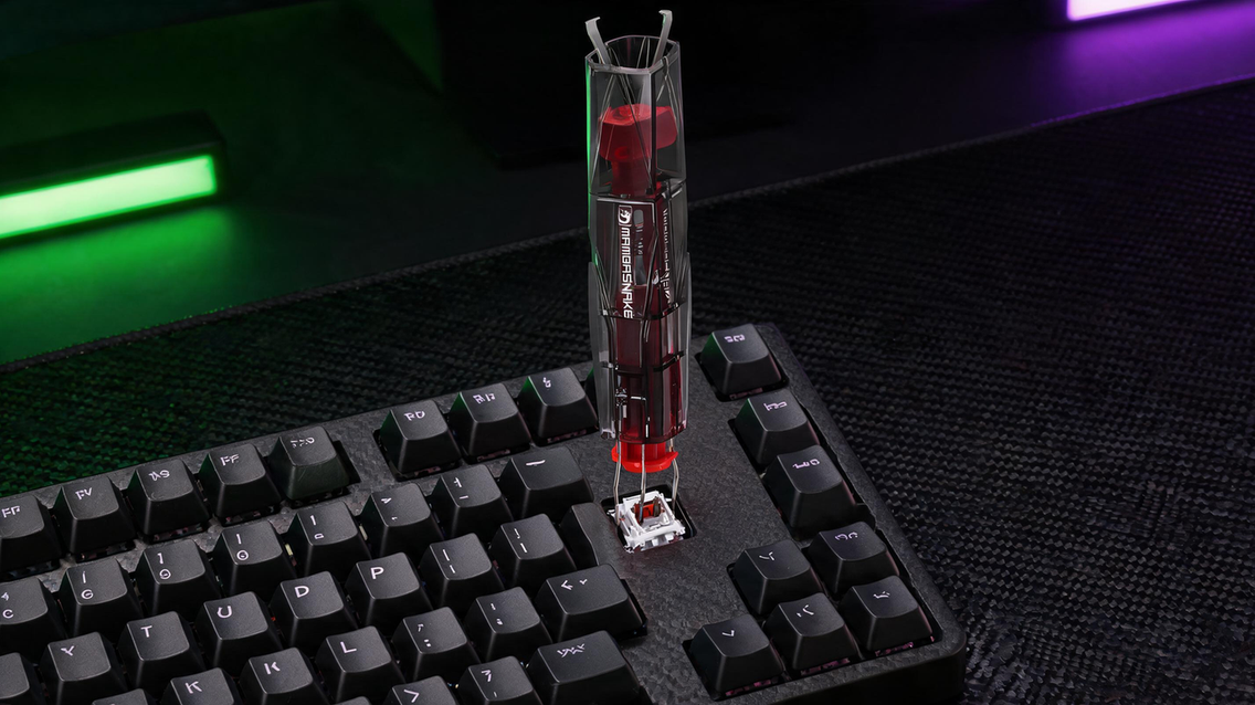 MAMBASNAKE KS01 2-in-1 keycap and switch puller positioned over a mechanical keyboard in a dark RGB-lit gaming setup