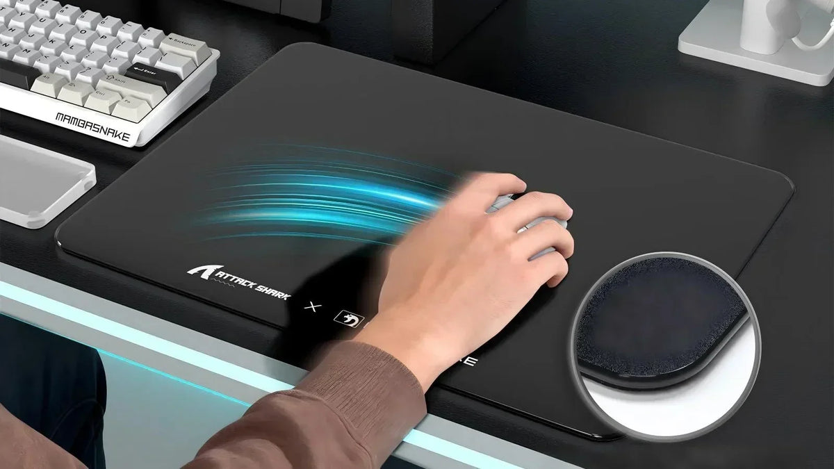 Hand moving a mouse on an ATTACK SHARK desk mat with a MAMBASNAKE keyboard nearby.