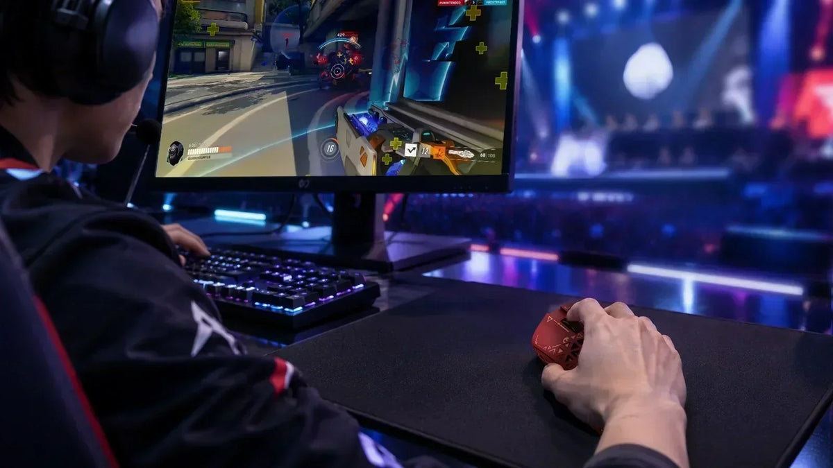 Professional esports player operating red MAMBASNAKE wireless gaming mouse at an Overwatch tournament arena, with neon stage lighting and spectator stands in background