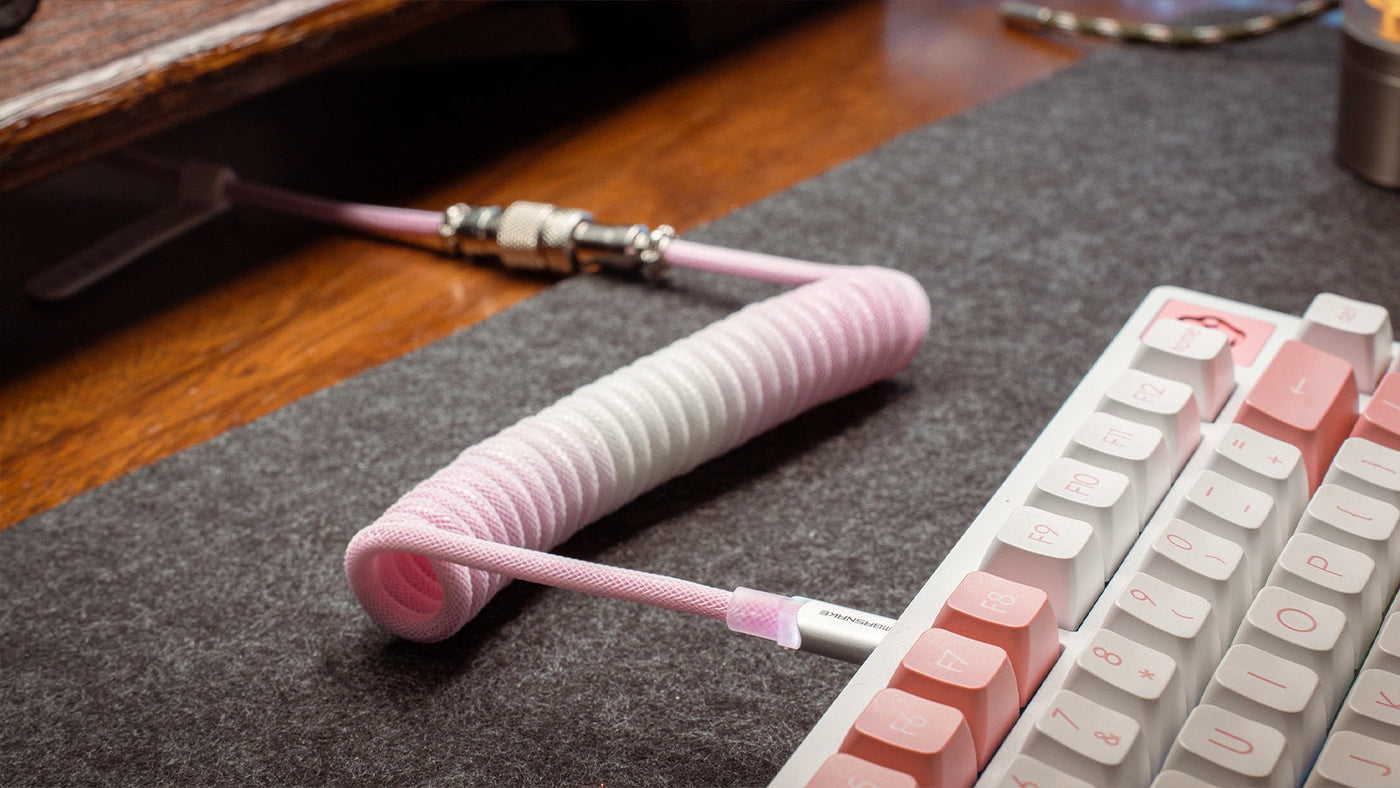 Pink braided keyboard cable connected to a white mechanical keyboard